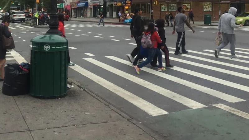 Pedestrians crossing a striped crosswalk at 2nd Avenue and East 116th Street in Manhattan.