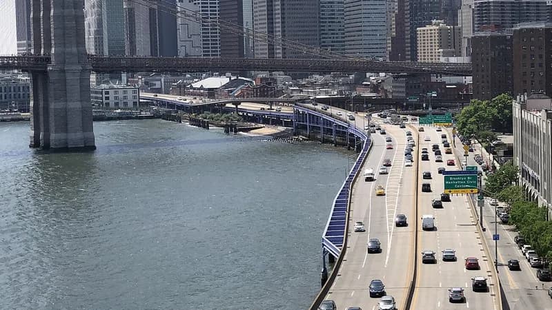 The FDR Drive curving along the East River below the Manhattan Bridge, with the Brooklyn Bridge and Lower Manhattan beyond.