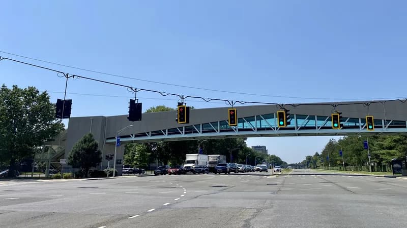 Traffic signals and a pedestrian bridge over Hempstead Turnpike in Uniondale, Nassau County, with traffic stopped at the light.