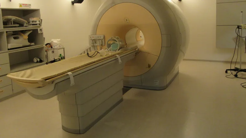 An empty MRI scanner room with the patient table extended from the scanner bore.