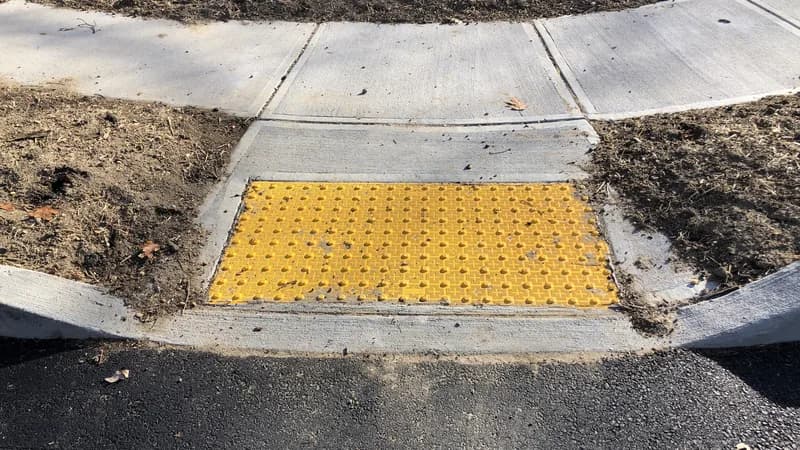 A concrete curb ramp with a yellow tactile warning pad at a crosswalk in Ewing, New Jersey.