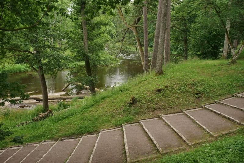 Outdoor steps following a tree-lined path beside a river.