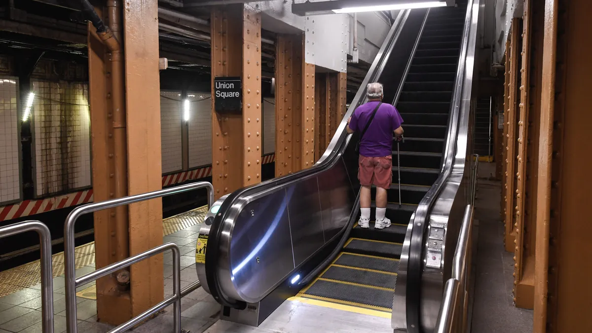 A rider standing on a newly installed escalator rising from the L train platform at the Union Square subway station.