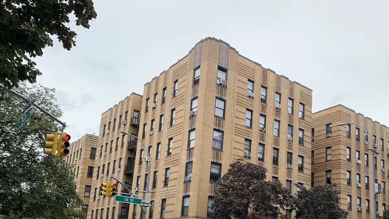 Six-story brick apartment buildings with window air conditioners on 74th Street in Jackson Heights, Queens.