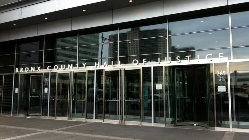 The glass entrance of the Bronx County Hall of Justice on East 161st Street, with the building name above the doors.