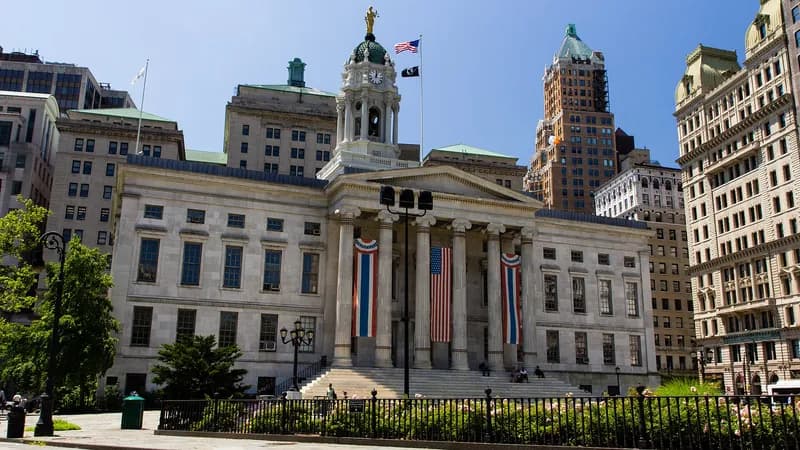Brooklyn Borough Hall, a columned civic building with flags, seen across the plaza in Downtown Brooklyn.