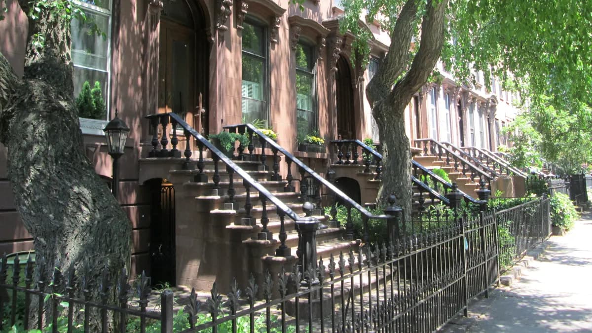 Brownstone stoops with iron railings along a tree-lined sidewalk in Prospect Heights, Brooklyn.