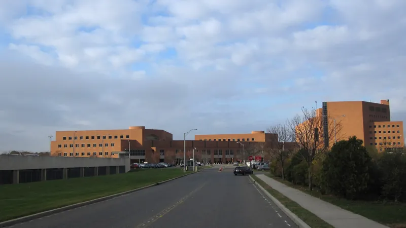 The brick Suffolk County court complex in Central Islip seen from its entrance road under a cloudy sky.