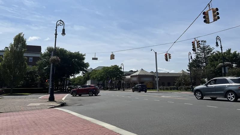 Traffic signals hanging over a Franklin Avenue intersection in Garden City, with a brick-paved corner in the foreground.
