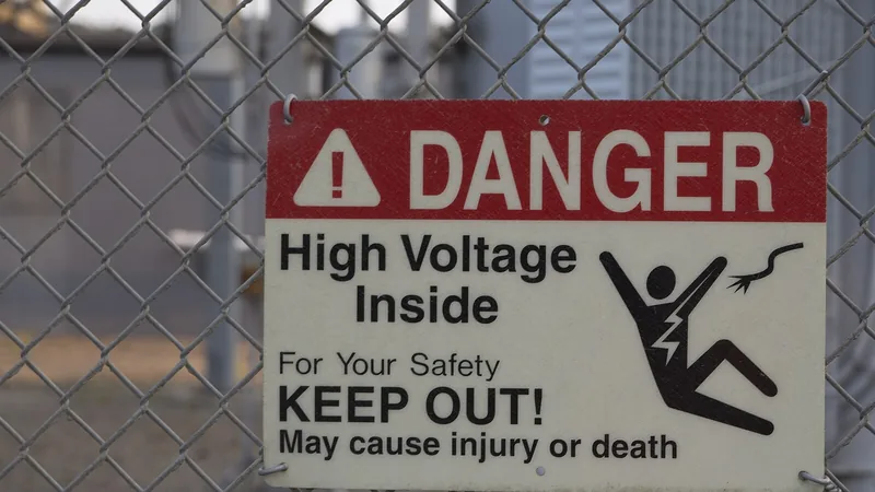 A red and white "Danger — High Voltage Inside — Keep Out" sign on a chain-link fence.