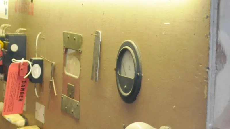 A red “Danger” lockout tag hanging from a switch on an electrical training panel beside an ammeter.