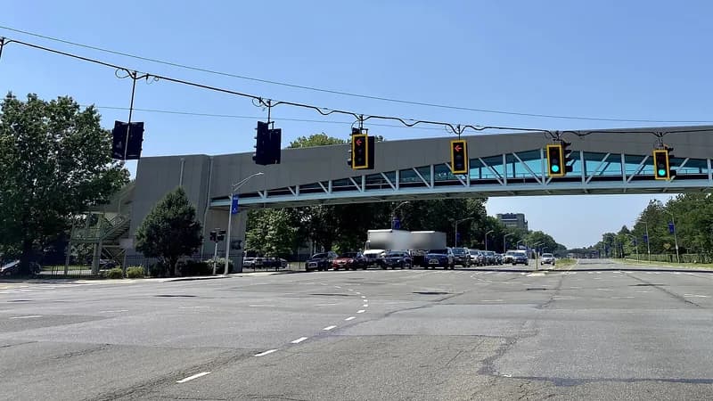 A wide signalized crossing of Hempstead Turnpike in Uniondale, with an enclosed pedestrian bridge over the road.