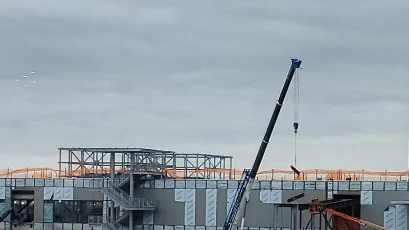 A new concourse under construction at LaGuardia Airport in Queens, with a steel frame on the roof and a mobile crane.