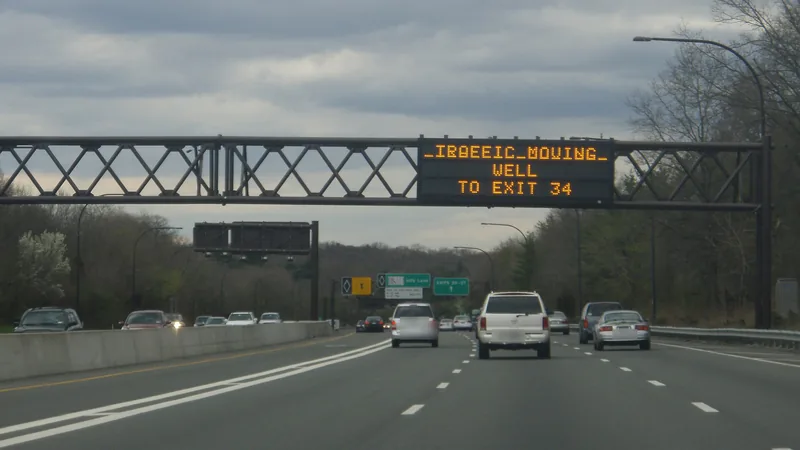 An overhead message sign spanning the Long Island Expressway in Nassau County, with cars in the eastbound lanes.
