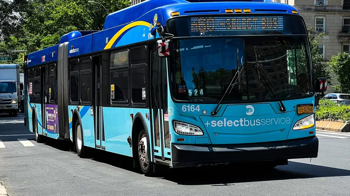 An MTA Select Bus Service articulated bus on the M60 route driving on a Manhattan street.