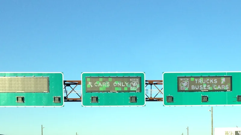 Overhead New Jersey Turnpike signs directing cars only to one roadway and trucks, buses and cars to the other.