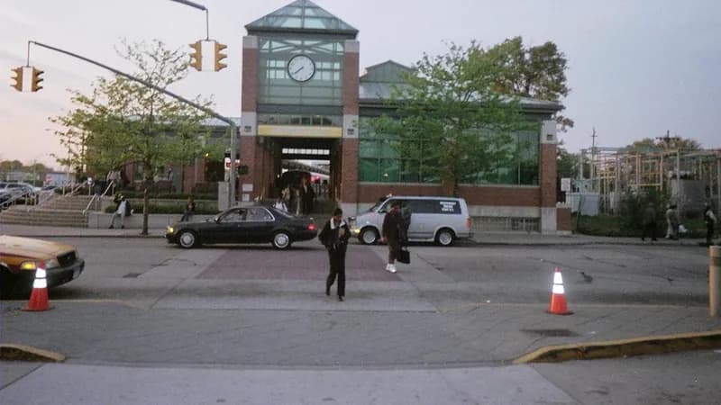 Commuters walking across a crosswalk at dusk outside the Hempstead LIRR station in Nassau County.
