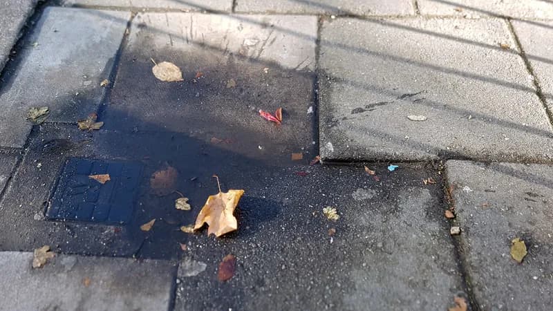 A paving slab raised above its neighbor where it meets a sunken utility cover, creating a trip edge.