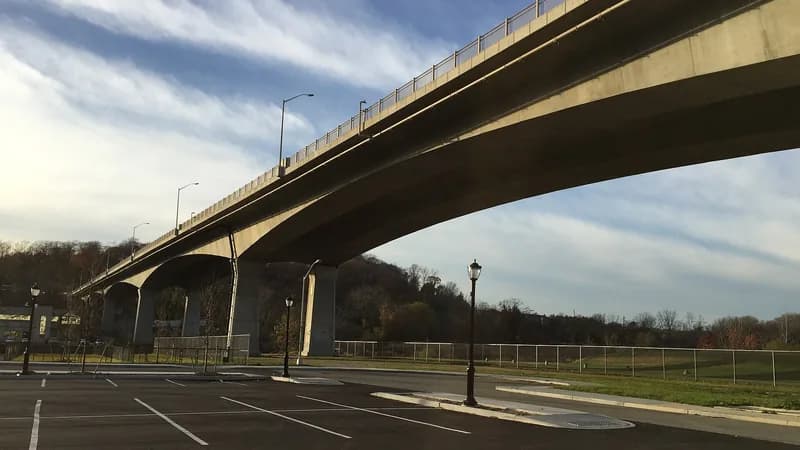 The concrete Roslyn Viaduct curving over Hempstead Harbor on Long Island, seen from below under a streaked sky.