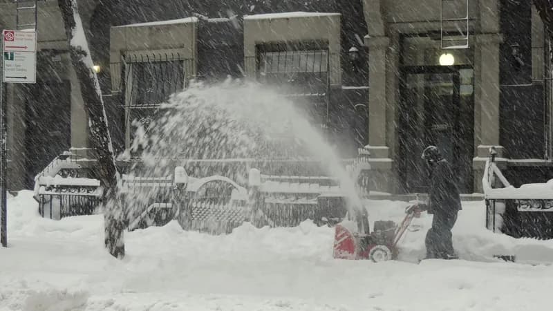 A worker using a snow blower to clear a Manhattan sidewalk on West 47th Street during a snowstorm.