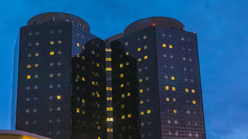 The twin towers of Stony Brook University Hospital at dusk, with lit windows.